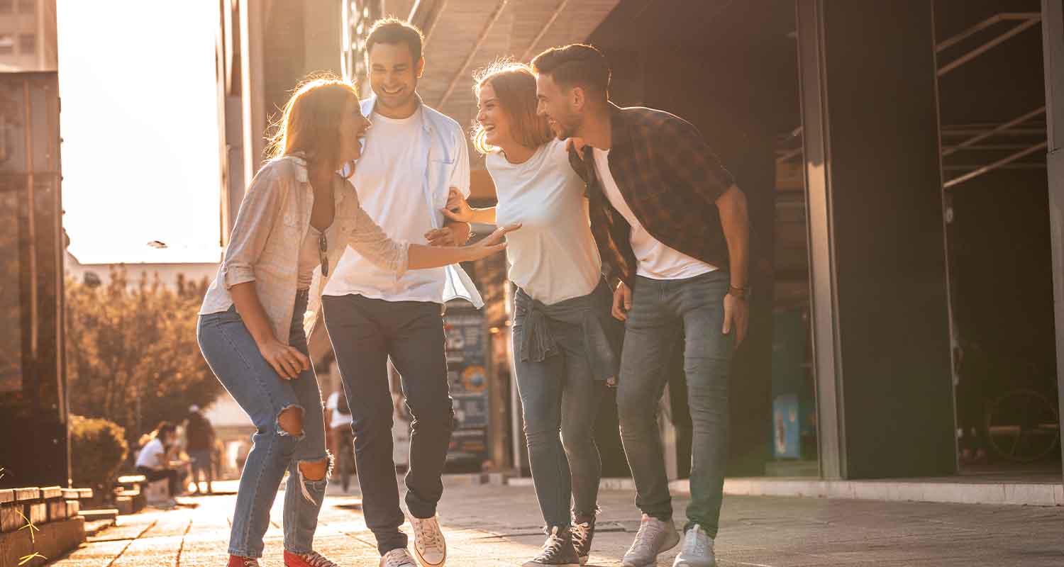 A group of 4 friends laugh whilst walking towards the camera